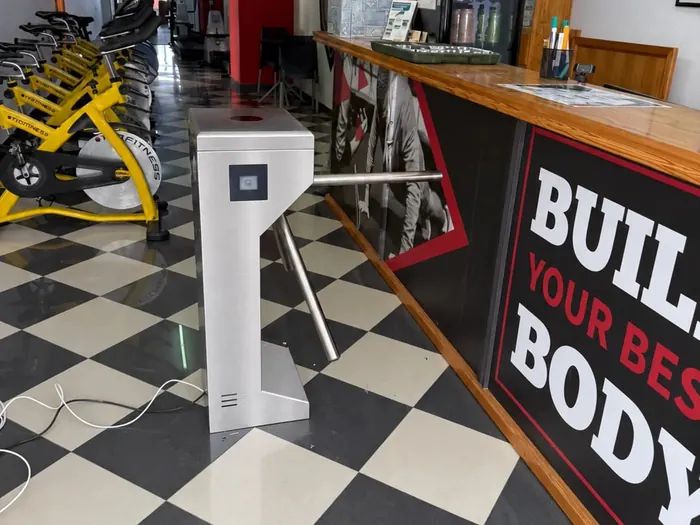 Torniquete trípode de acero inoxidable con lector QR en la recepción de un gimnasio