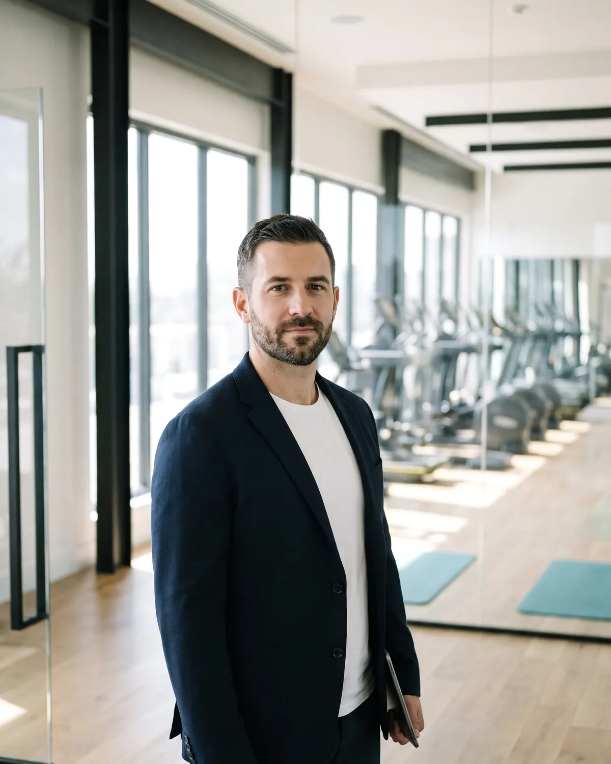 Un gerente con americana y tablet en una sala de fitness amplia y luminosa